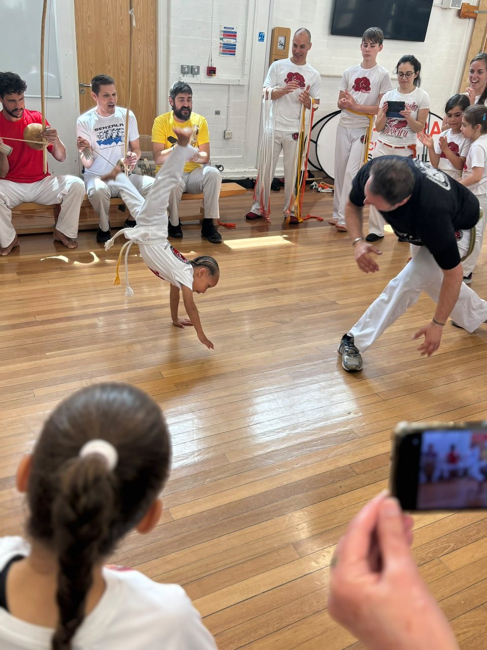 Two players exchange capoeira movements while the surrounding roda watches.
